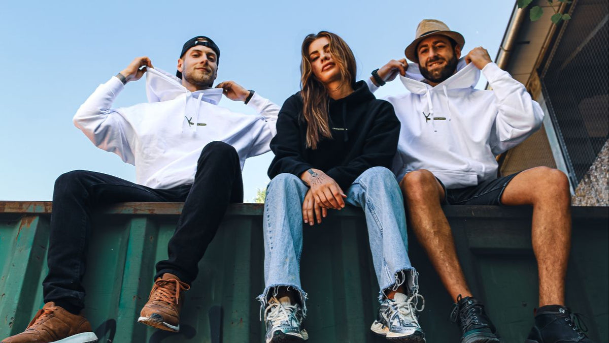 Drei Personen in YAFATAR Hoodies sitzen auf einem Container